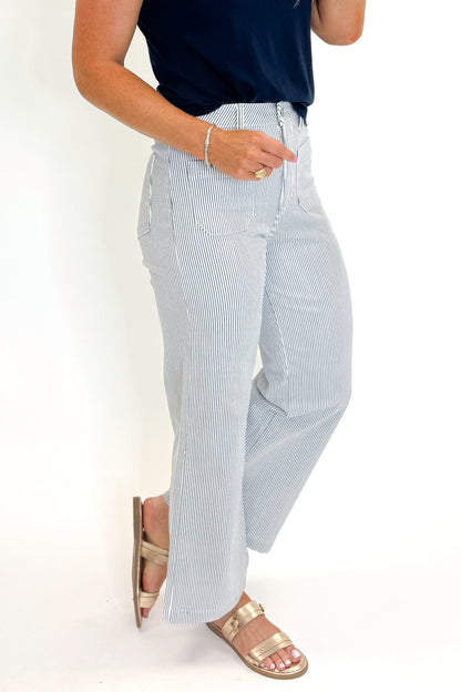 Side view of woman wearing Swagger Boutique’s Cream &amp; Blue Striped Jeans With Patch Pocket by Just Black Denim with blue Z Supply top against white studio background.