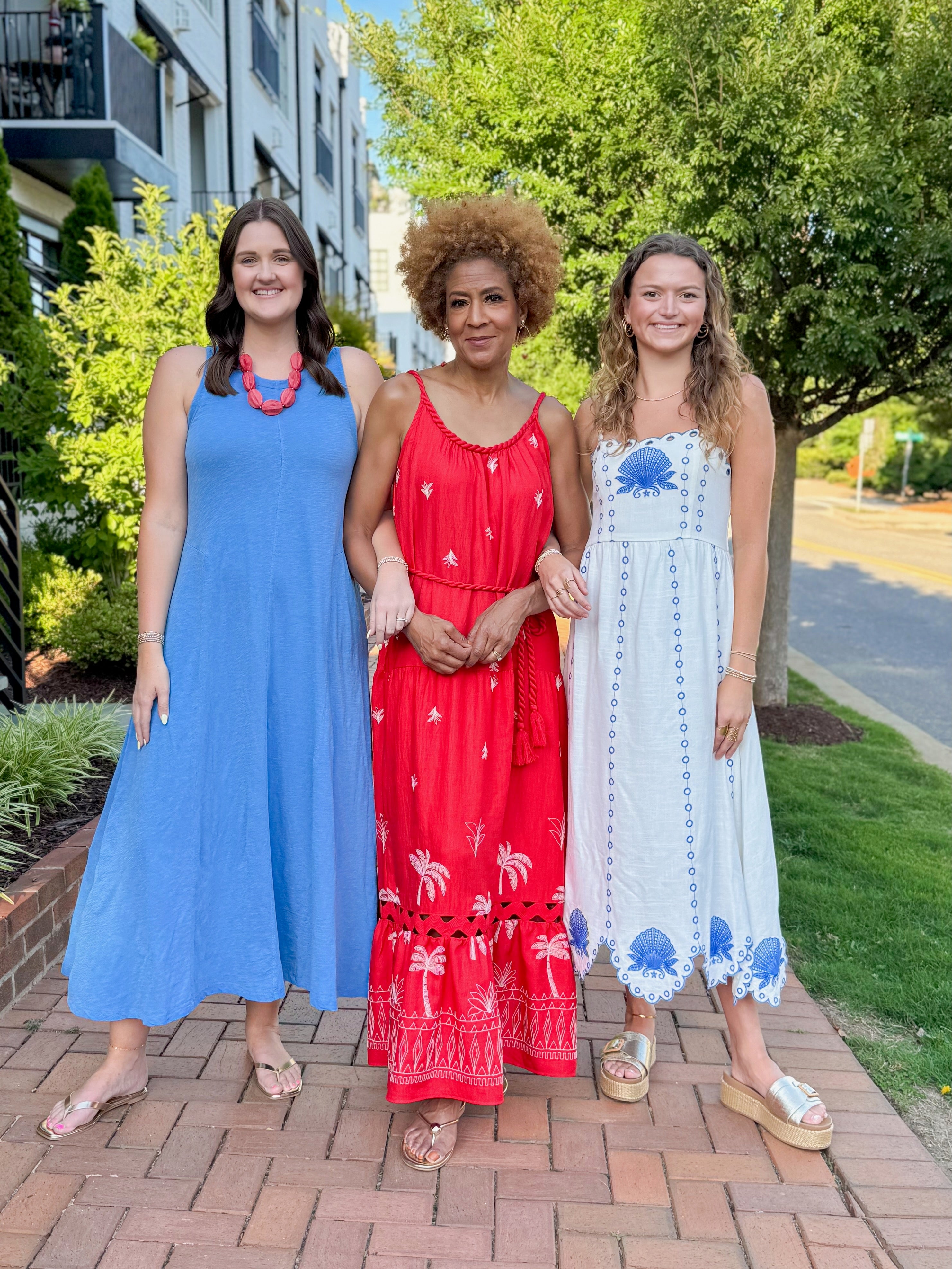 Front view of woman wearing Swagger Boutique’s Cream &amp; Blue Shell Embroidered Midi Dress with two other women walking outside.