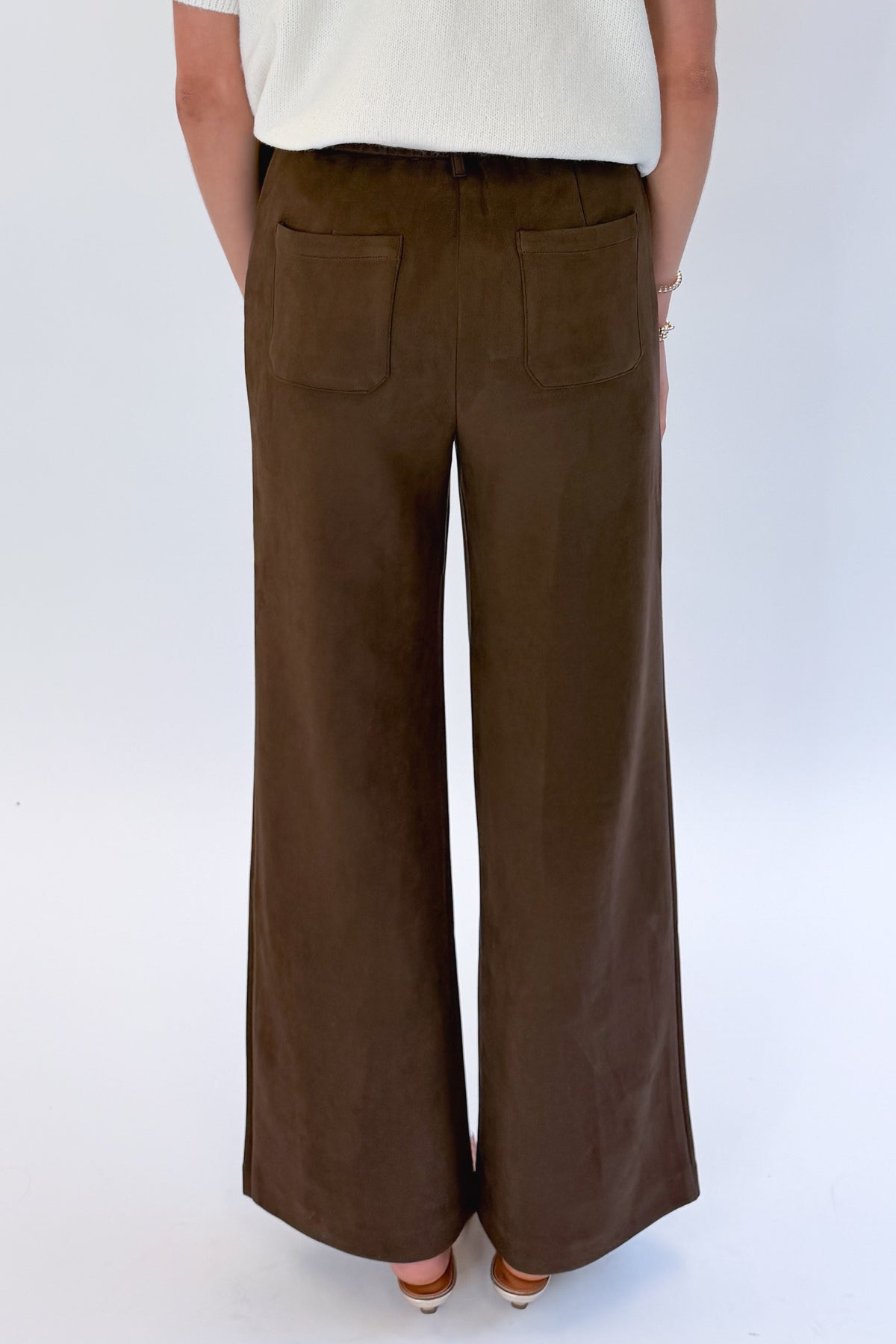 Back detail view of woman wearing Swagger Boutique’s Cream &amp; Brown Fair Isle Button Up Short Sleeve Sweater with Chocolate Brown Suede Pants against white studio background. 
