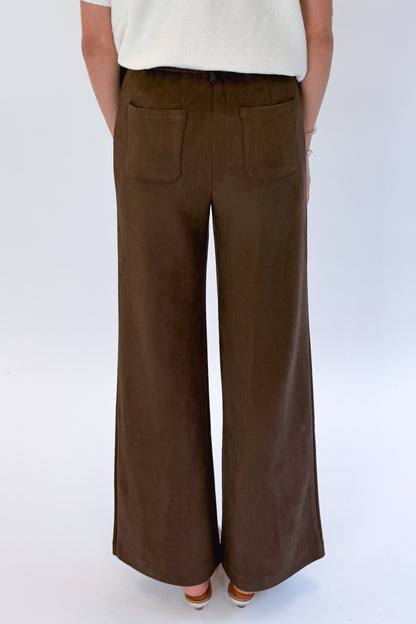 Back detail view of woman wearing Swagger Boutique’s Cream &amp; Brown Fair Isle Button Up Short Sleeve Sweater with Chocolate Brown Suede Pants against white studio background. 