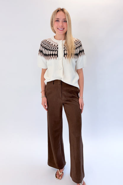 Front view of woman wearing Swagger Boutique’s Cream &amp; Brown Fair Isle Button Up Short Sleeve Sweater with Chocolate Brown Suede Pants against white studio background. 
