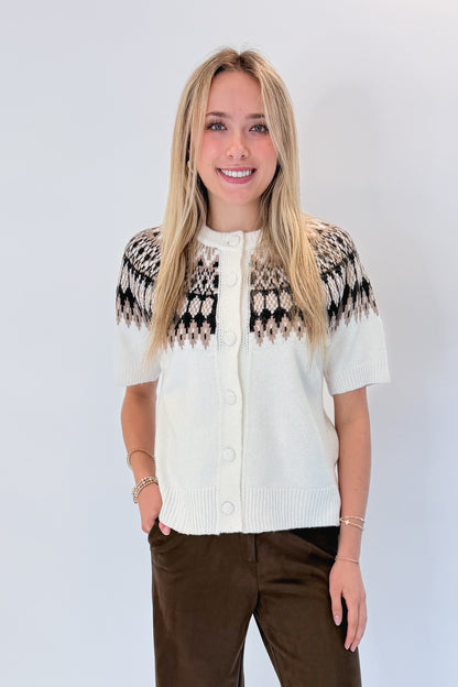 Front view of woman wearing Swagger Boutique’s Cream &amp; Brown Fair Isle Button Up Short Sleeve Sweater with Chocolate Brown Suede Pants against white studio background. 