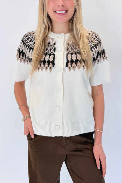 Front detail view of woman wearing Swagger Boutique’s Cream &amp; Brown Fair Isle Button Up Short Sleeve Sweater with Chocolate Brown Suede Pants against white studio background. 
