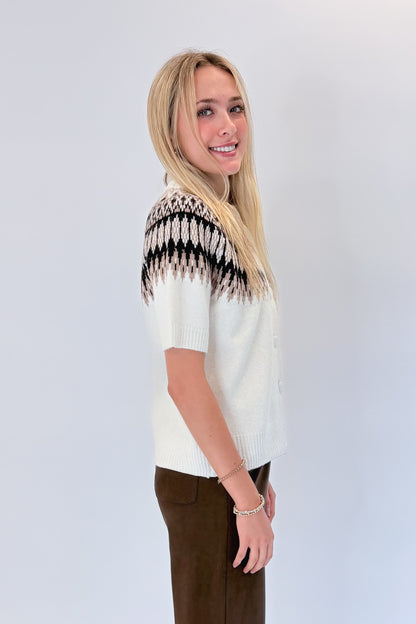 Side view of woman wearing Swagger Boutique’s Cream &amp; Brown Fair Isle Button Up Short Sleeve Sweater with Chocolate Brown Suede Pants against white studio background. 