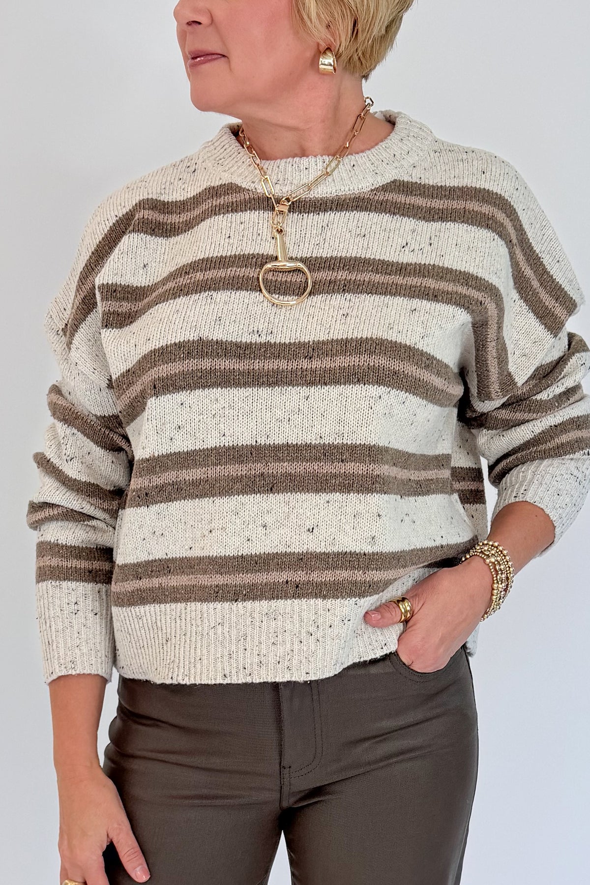 Front detail view of woman wearing Swagger Boutique’s Cream &amp; Brown Multi Striped Sweater with Meg Coated Wide Leg Jeans in Toffee by Kut from the Kloth against white studio background.
