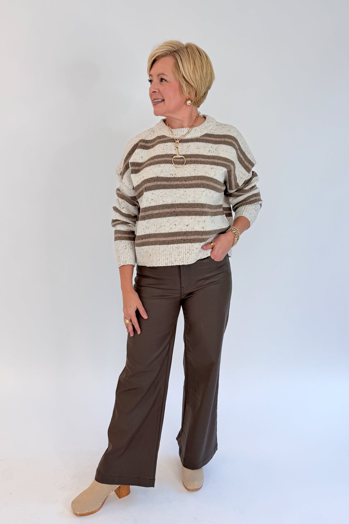 Front view of woman wearing Swagger Boutique’s Cream &amp; Brown Multi Striped Sweater with Meg Coated Wide Leg Jeans in Toffee by Kut from the Kloth against white studio background.