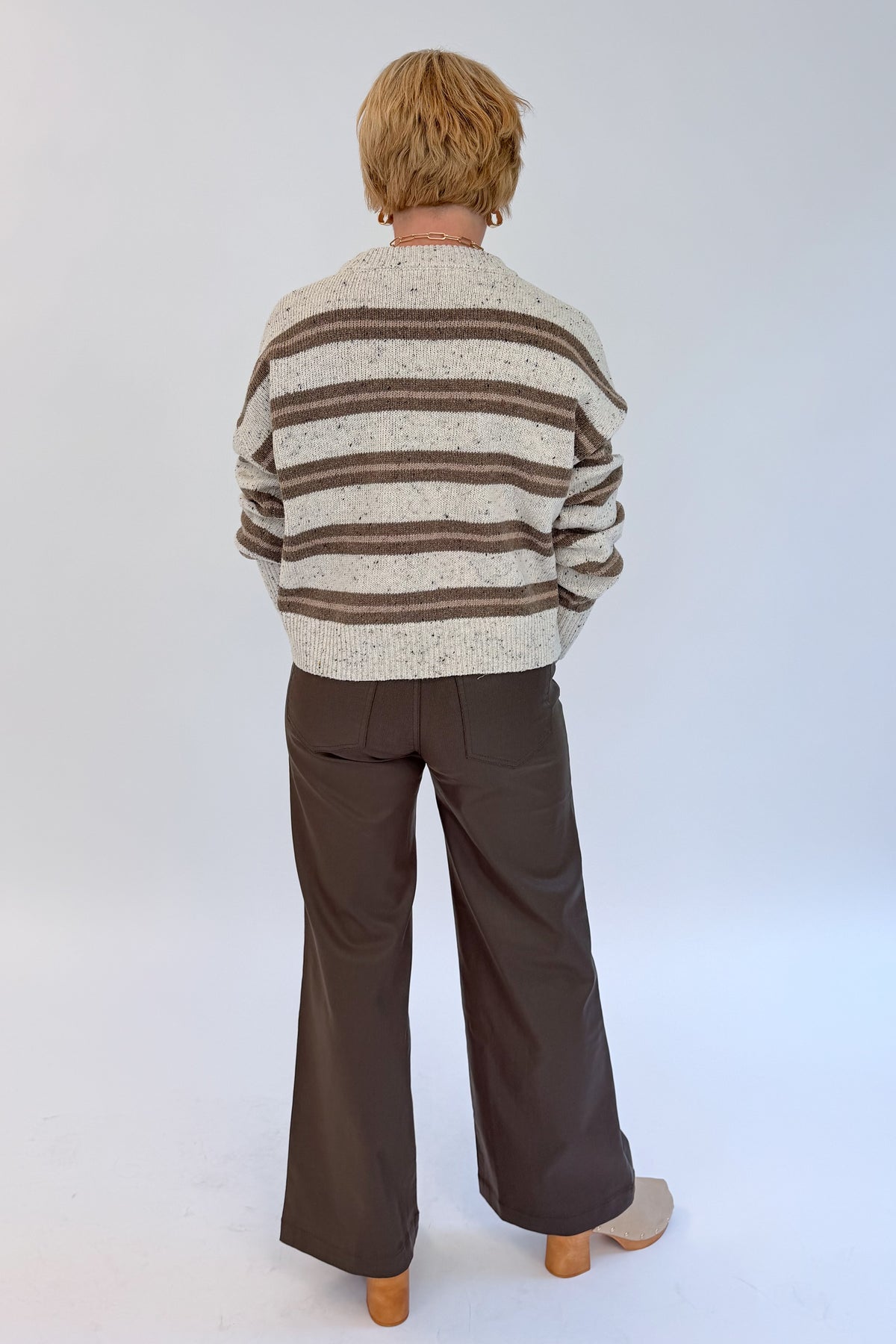 Back view of woman wearing Swagger Boutique’s Cream &amp; Brown Multi Striped Sweater with Meg Coated Wide Leg Jeans in Toffee by Kut from the Kloth against white studio background.