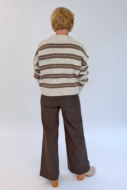 Back view of woman wearing Swagger Boutique’s Cream &amp; Brown Multi Striped Sweater with Meg Coated Wide Leg Jeans in Toffee by Kut from the Kloth against white studio background.