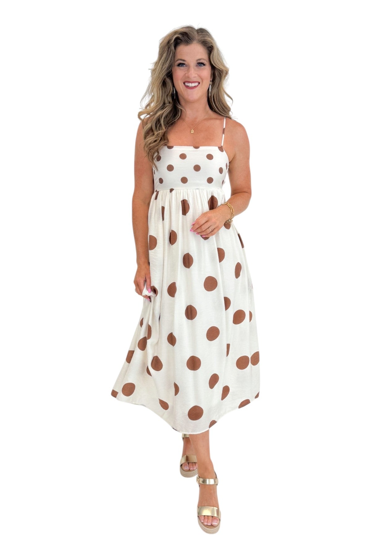 Front view of woman wearing Swagger Boutique’s Cream &amp; Brown Polka Dot Midi Dress with sandals against white studio background.