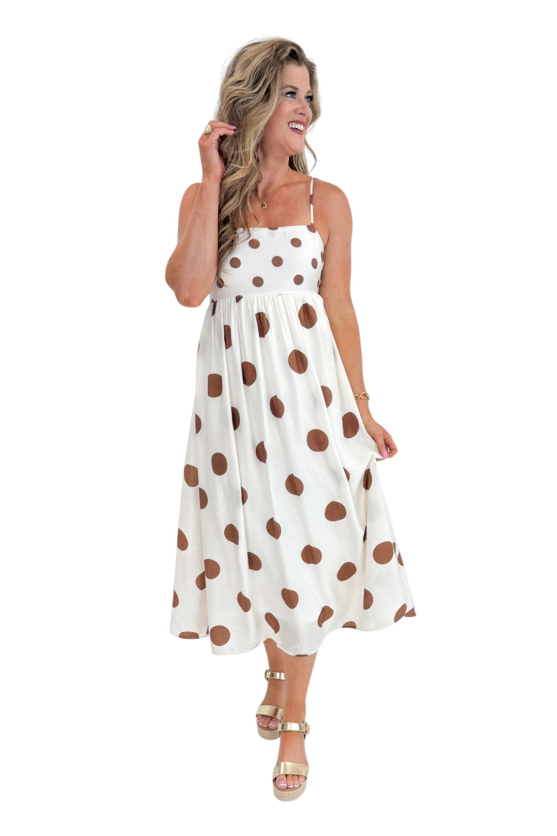 Front view of woman wearing Swagger Boutique’s Cream &amp; Brown Polka Dot Midi Dress with sandals against white studio background.