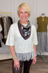 Front view of woman wearing Swagger Boutique’s Cream Fringe Short Sleeve Sweater with jeans with clothing hanging in the background.