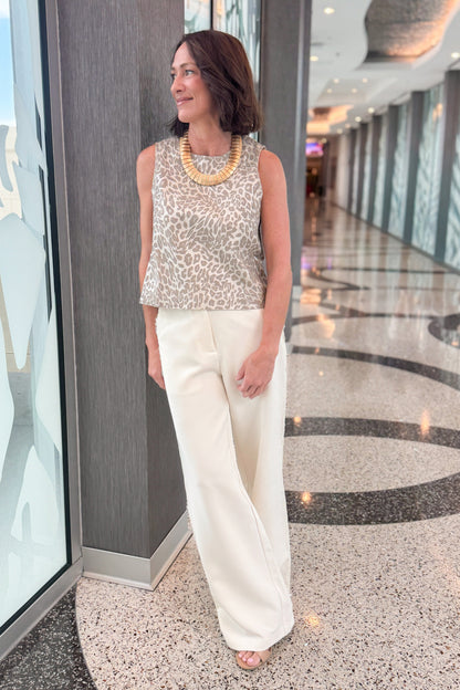 Front detail view of woman wearing Swagger Boutique’s Cream Lace Lined Pants with Metallic leopard print tank standing in a building hallway.