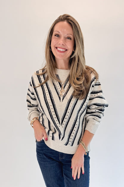 Front view of woman wearing Swagger Boutique’s Cream &amp; Navy Chevron Sweater with jeans against white studio background.