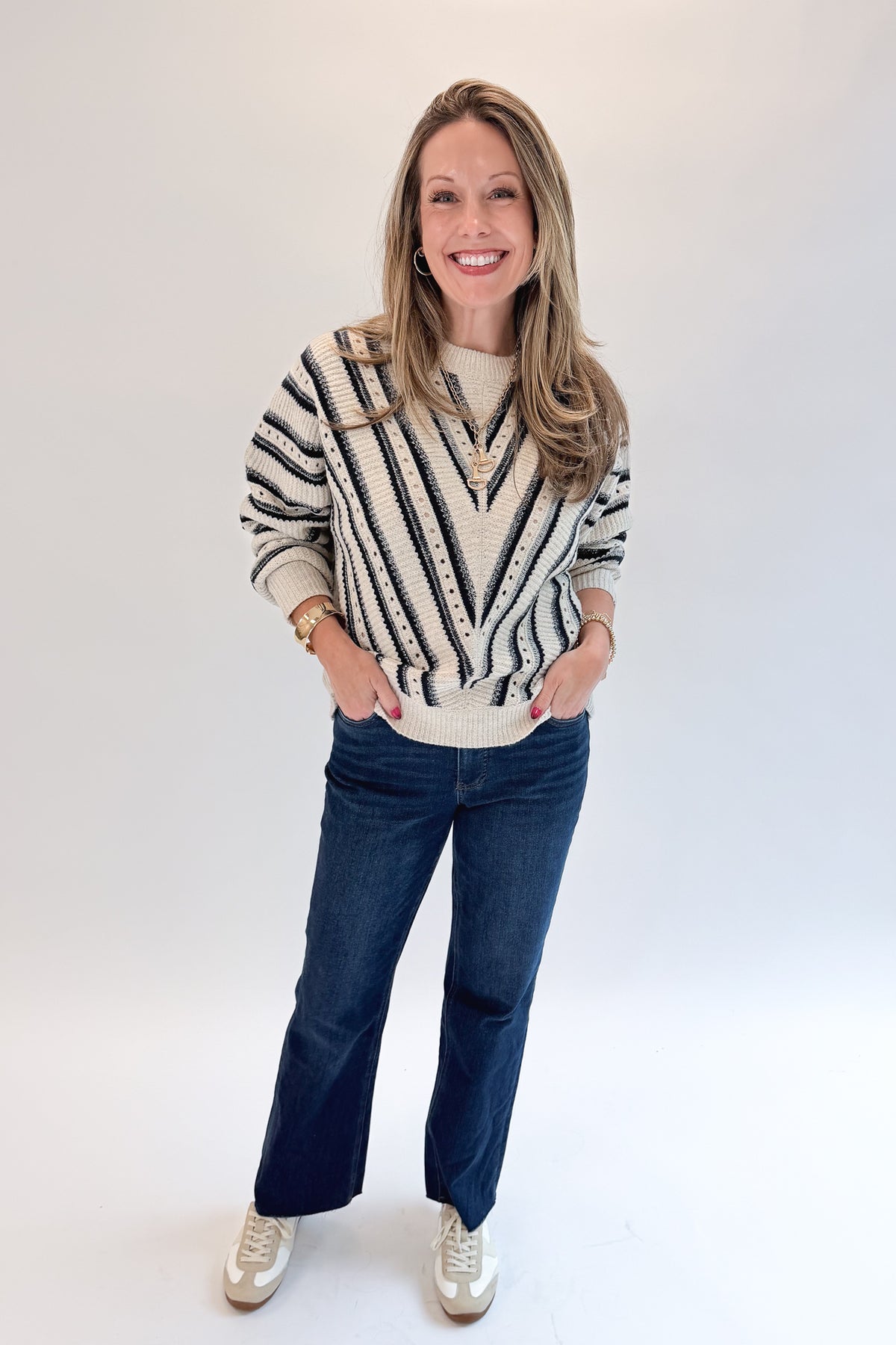 Front view of woman wearing Swagger Boutique’s Cream &amp; Navy Chevron Sweater with jeans against white studio background.