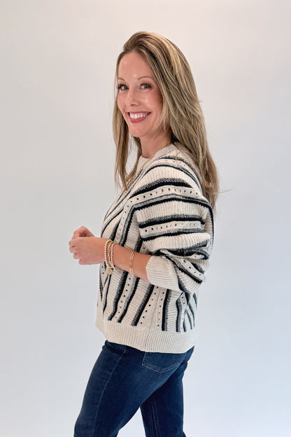 Side view of woman wearing Swagger Boutique’s Cream &amp; Navy Chevron Sweater with jeans against white studio background.