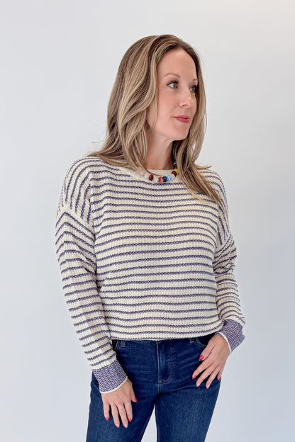 Front view of woman wearing Swagger Boutique’s Cream &amp; Purple Striped Sweater with jeans against white studio background.