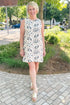 Front view of woman wearing Swagger Boutique’s Cream, Taupe & Black Floral Printed Shift Dress with sandals outside at a park.