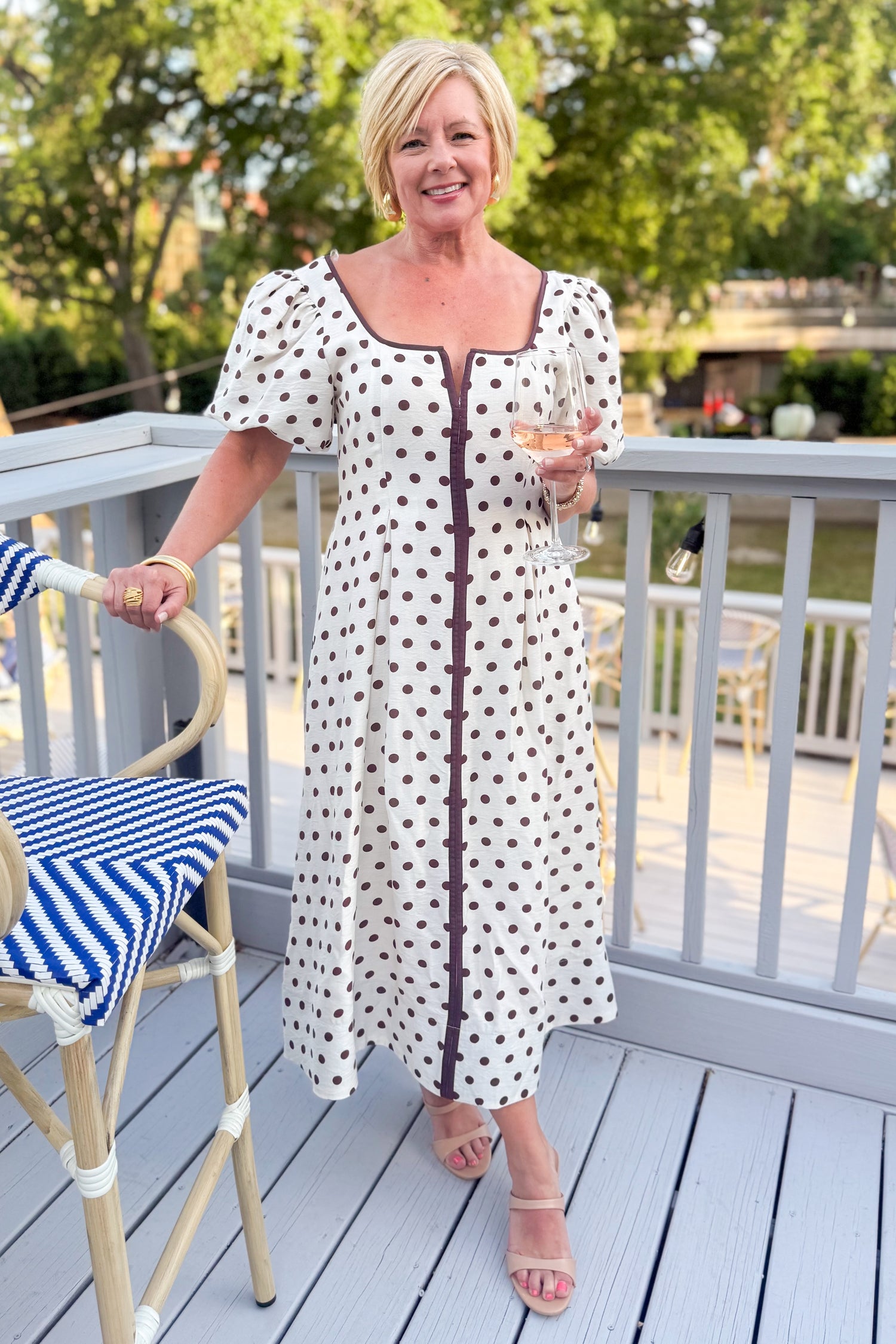 Front view of woman wearing Cream With Brown Stripe Detail Polka Dot Midi Dress by Entro outside at a restaurant.