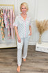 Woman wearing a patterned pajama set in a room with clothing racks and decor.