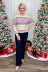 Woman in a festive sweater standing between two decorated Christmas trees with presents underneath.