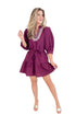 Woman wearing a purple dress with white embroidery on a white background