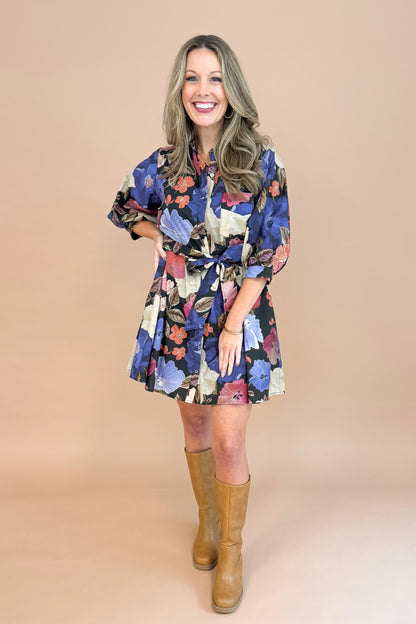 Woman in Black button-up mini dress with colorful floral print, featuring puff sleeves and self-tie waist by Entro