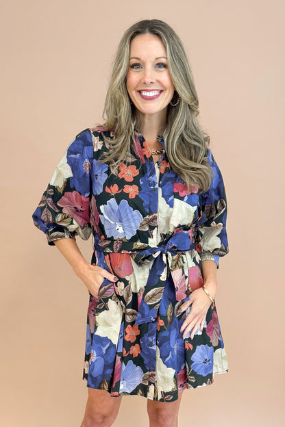 Woman in Black button-up mini dress with colorful floral print, featuring puff sleeves and self-tie waist by Entro