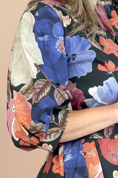 Woman in Black button-up mini dress with colorful floral print, featuring puff sleeves and self-tie waist by Entro