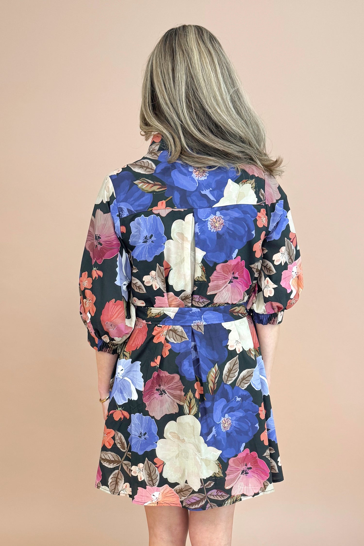 Woman in Black button-up mini dress with colorful floral print, featuring puff sleeves and self-tie waist by Entro