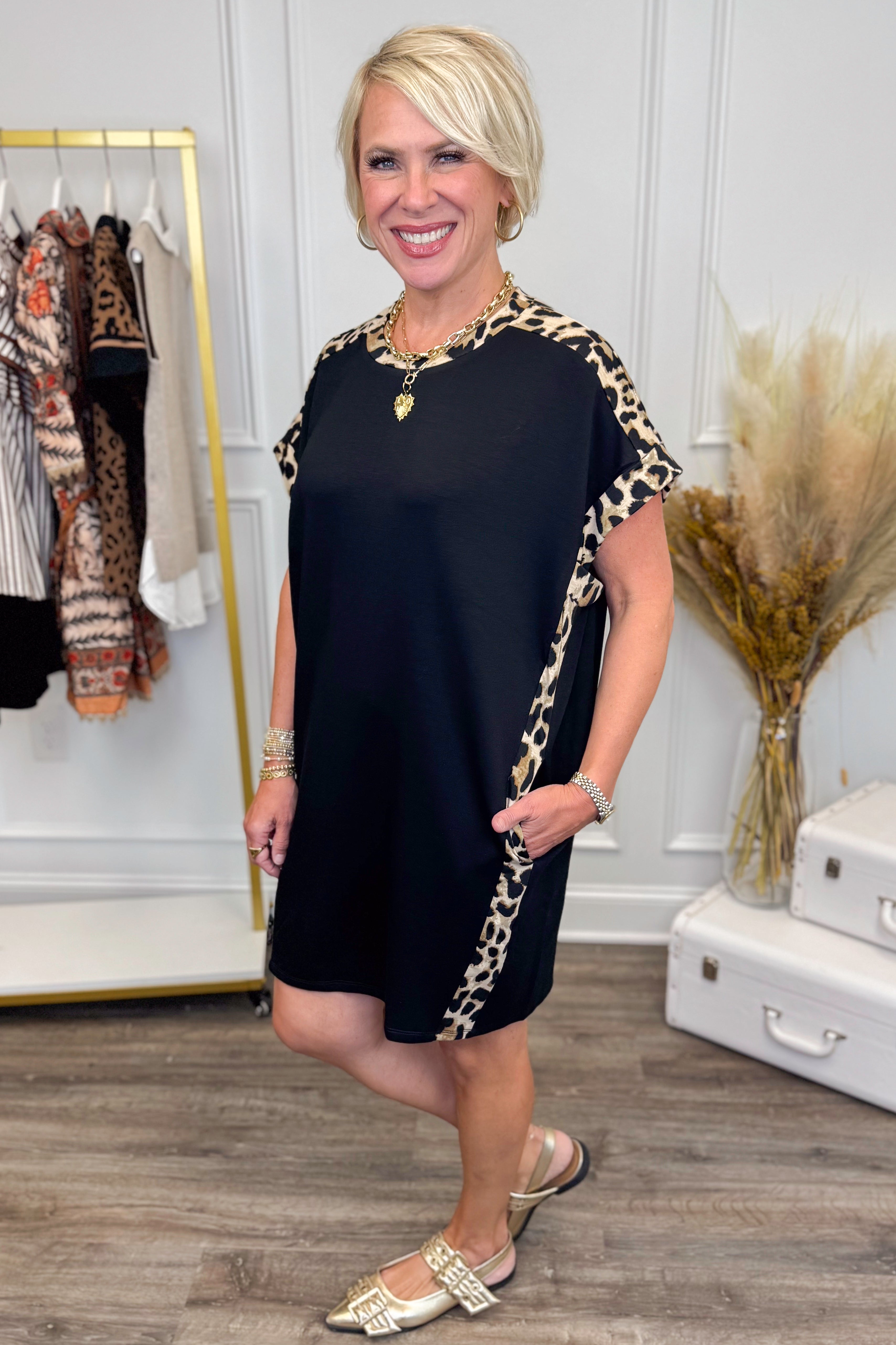 Side view of black short sleeve mini dress showing leopard print contrast trim and side pockets.