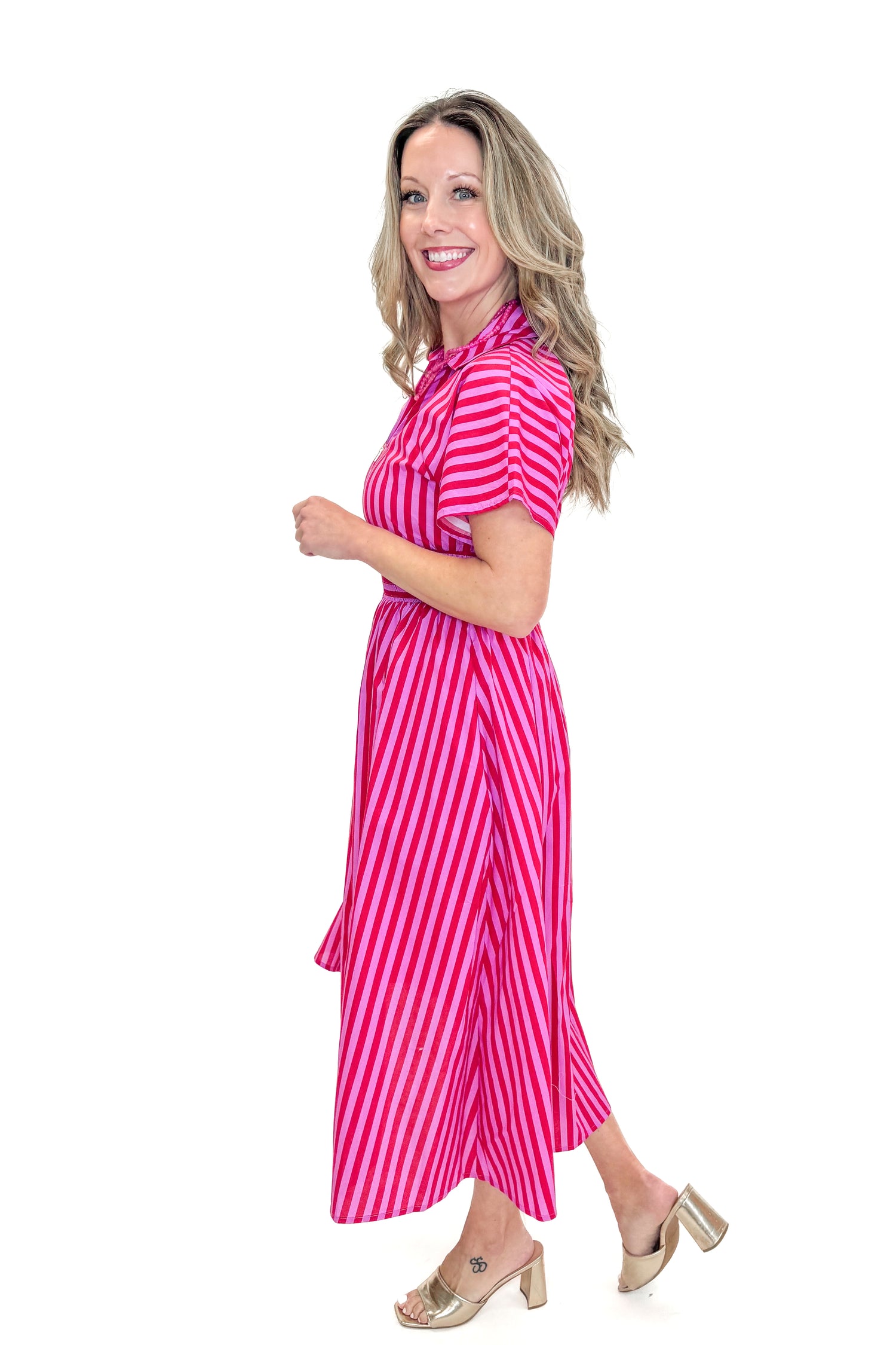 Side view of woman wearing Red &amp; Pink Striped Center Zip Midi Dress by Entro against white studio background.