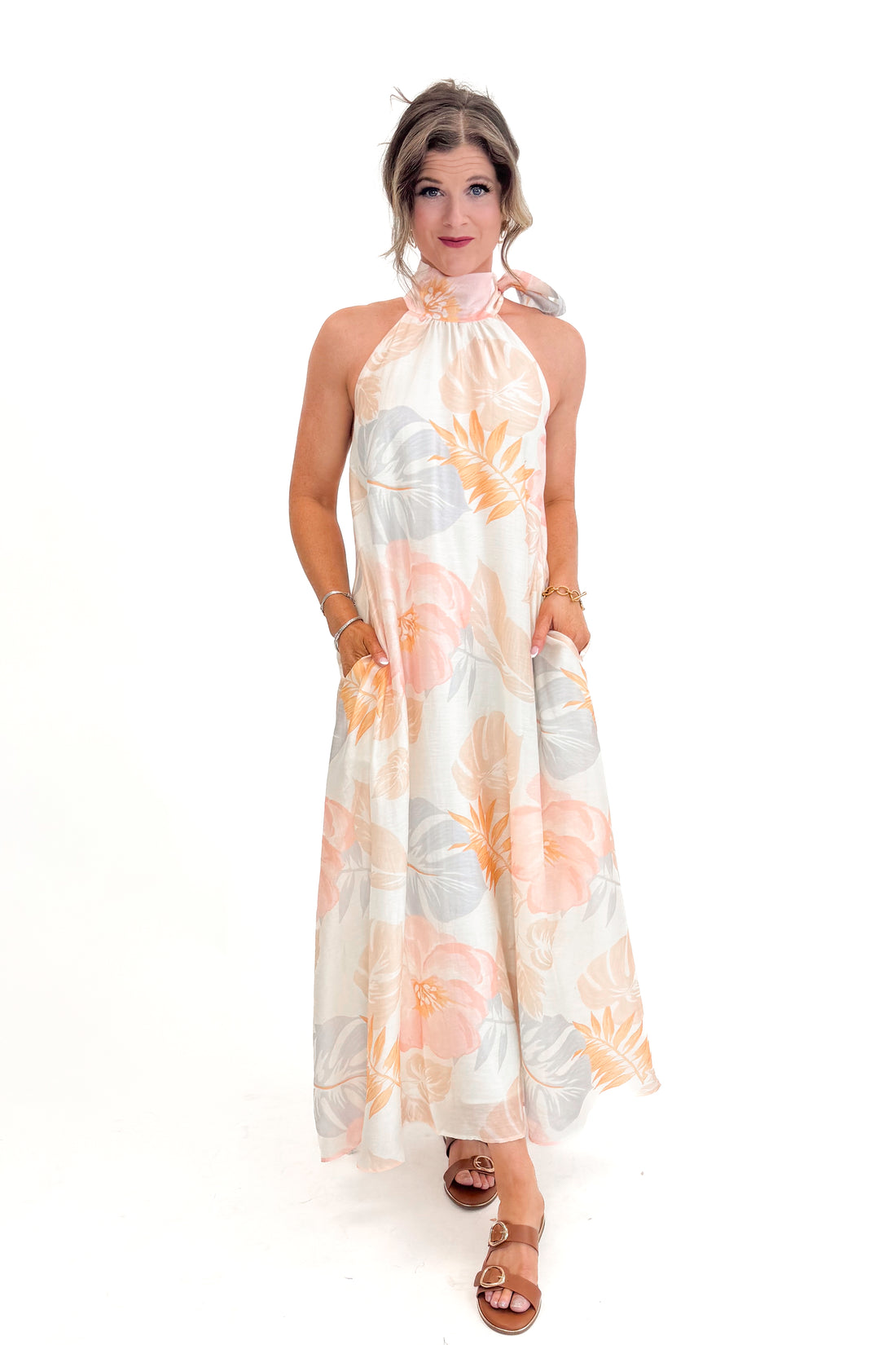 Front view of woman wearing Multi Tropical Printed Tie Neck Maxi Dress by Entro with sandals against white studio background.