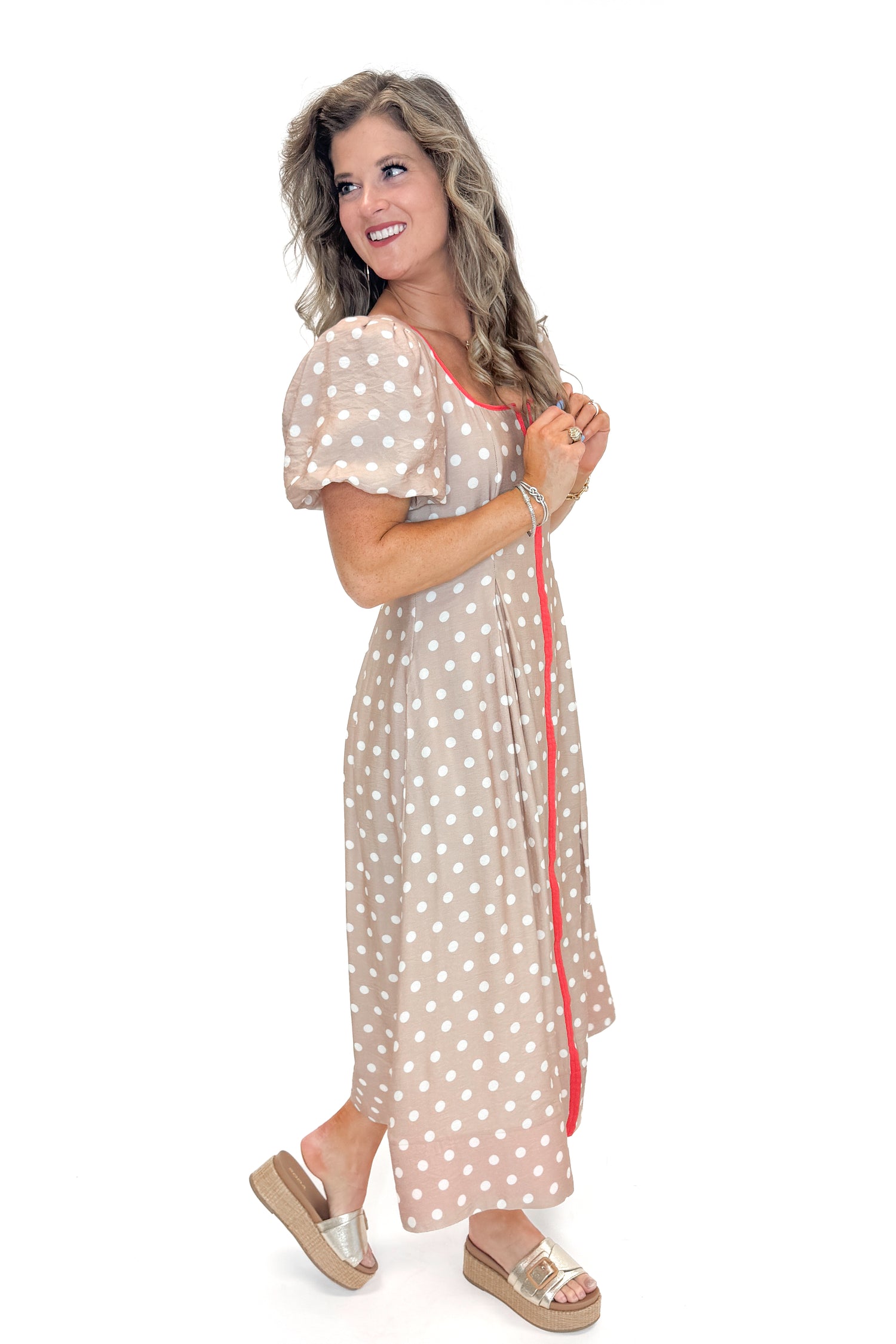 Side view of woman wearing Sand With Red Stripe Detail Polka Dot Midi Dress by Entro against white studio background.