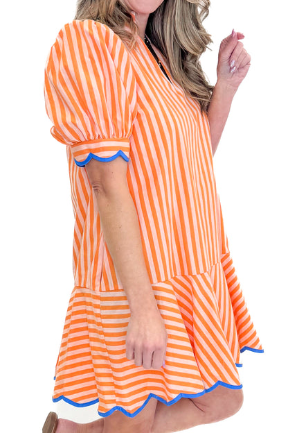 Side detail view of woman wearing Orange Stripe With Blue Lining Dress by Entro with sandals against white studio background.