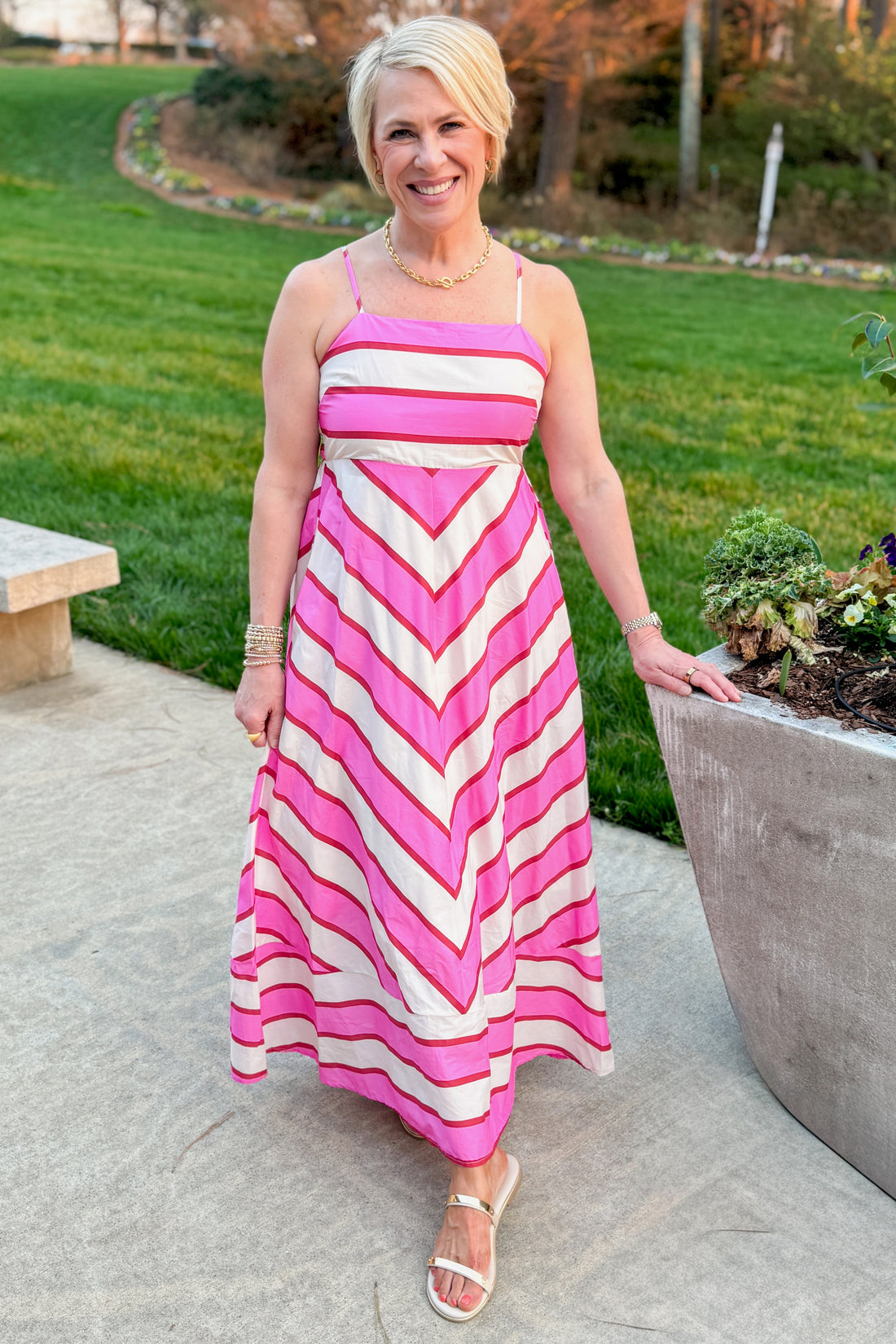 Front view of woman wearing Cream &amp; Pink Striped Midi Dress by Entro with sandals outside at a garden.