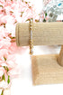 Gold beaded bracelet on a burlap roll with pink flowers and disco ball in the background
