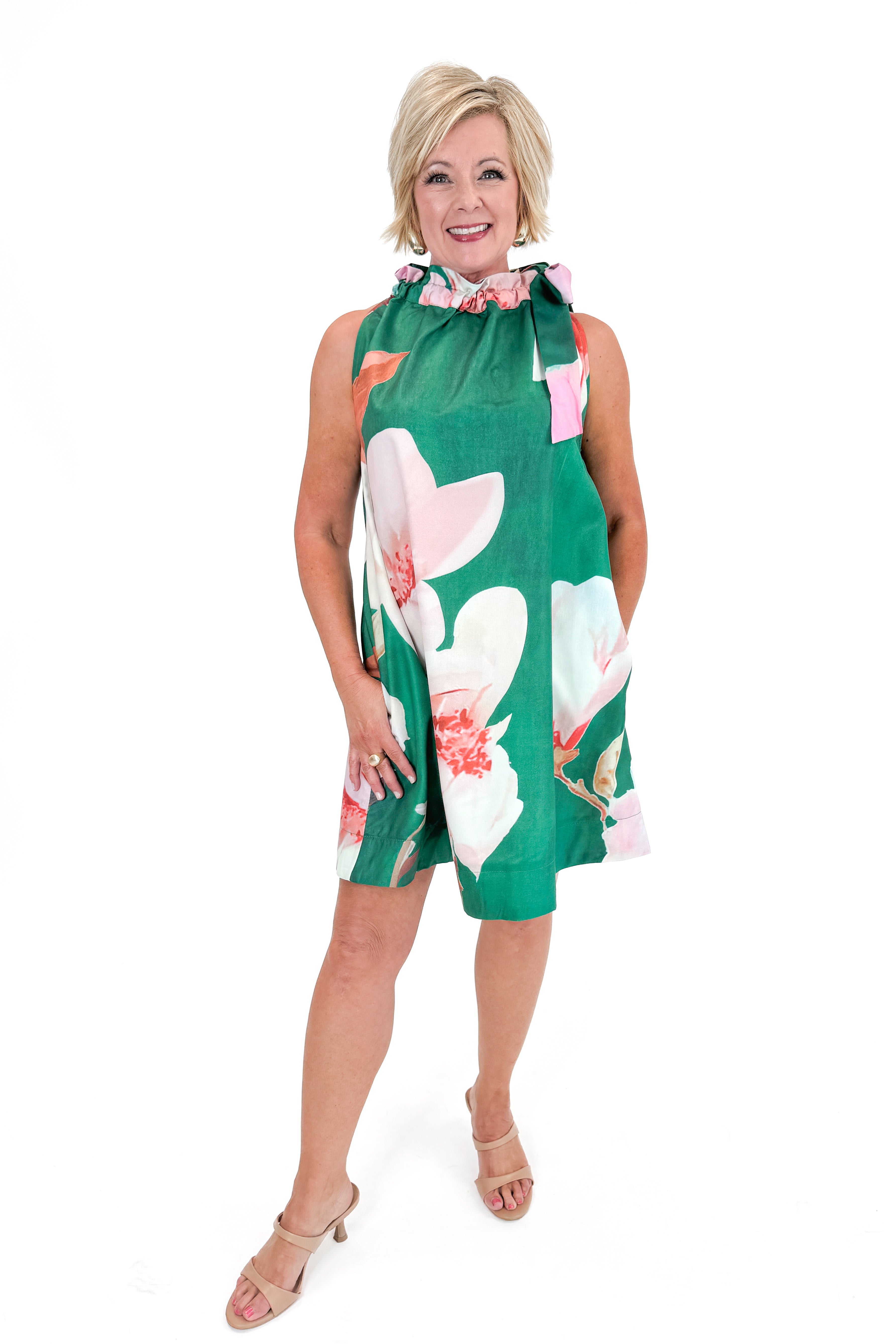 Front view of woman wearing Green Floral Tie Neck Mini Dress against white studio background.