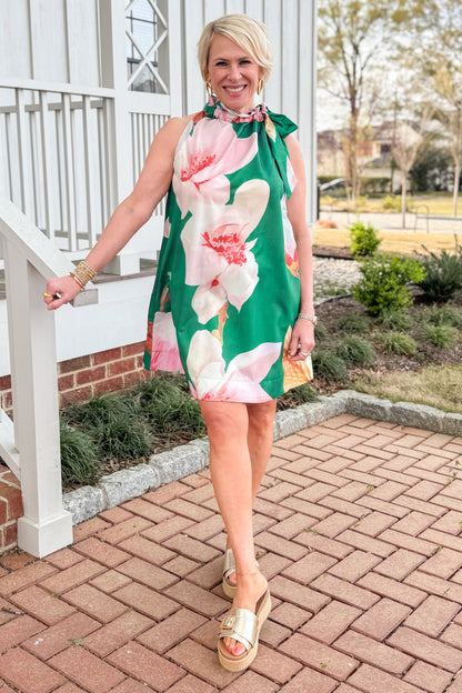 Front view of woman wearing Green Floral Tie Neck Mini Dress walking outside.