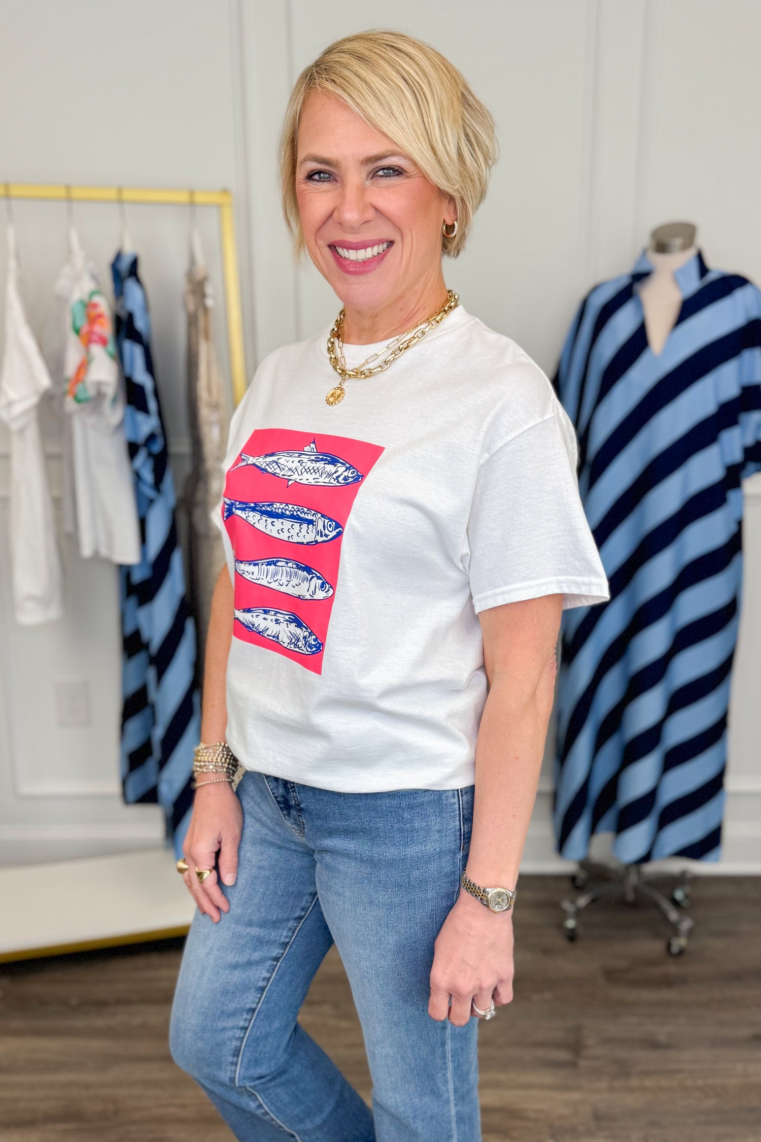 Woman wearing a white t-shirt with a colorful graphic design in a clothing store.