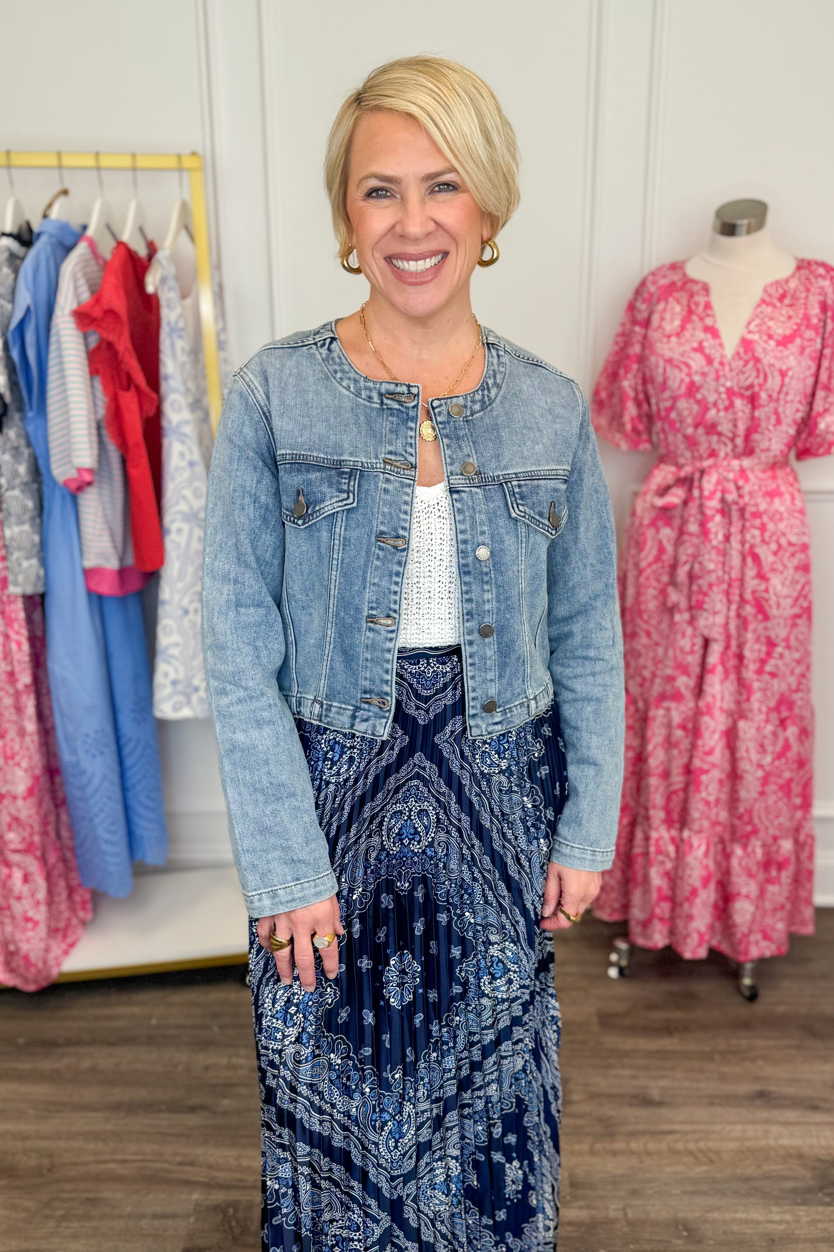 Front view of woman wearing Medium Wash Collarless Denim Jacket by Just Black Denim with top and skirt. 