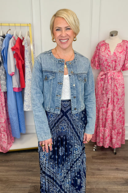 Front view of woman wearing Medium Wash Collarless Denim Jacket by Just Black Denim with top and skirt. 