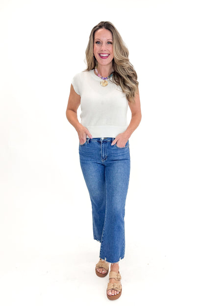 Front view of woman wearing Medium Wash Kick Crop Jeans by Just Black Denim with sweater against white studio background.