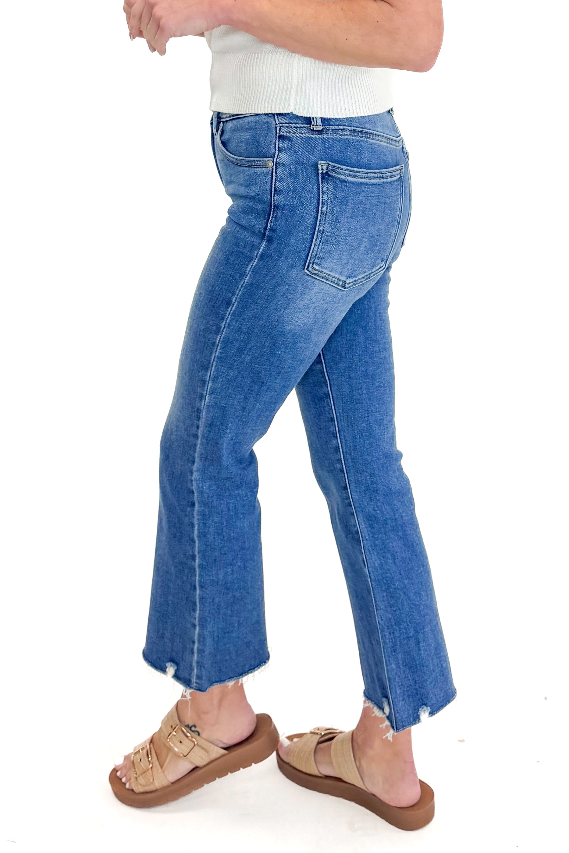 Side view of woman wearing Medium Wash Kick Crop Jeans by Just Black Denim with sweater against white studio background.