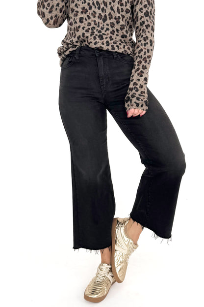 Front view of woman wearing washed black jeans and print top against white studio background.
