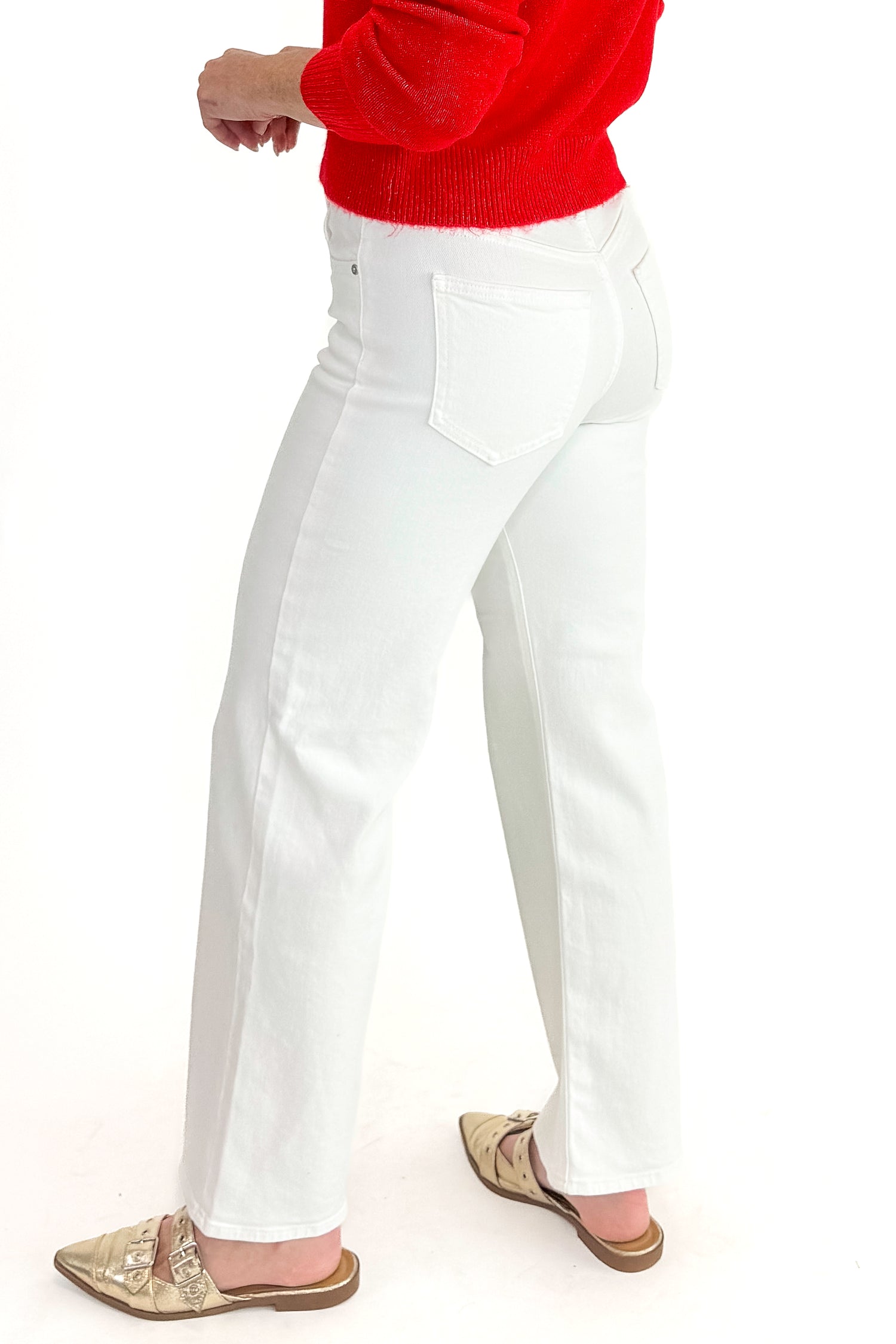Side detail view of woman wearing red sweater with White Straight Leg Jeans by Just Black Denim against white studio background.