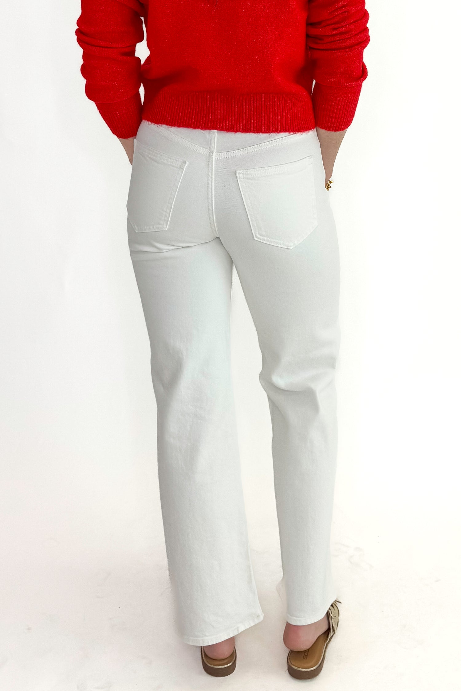Back view of woman wearing red sweater with White Straight Leg Jeans by Just Black Denim against white studio background.