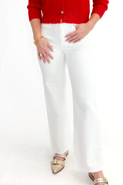 Front detail view of woman wearing red sweater with White Straight Leg Jeans by Just Black Denim against white studio background.