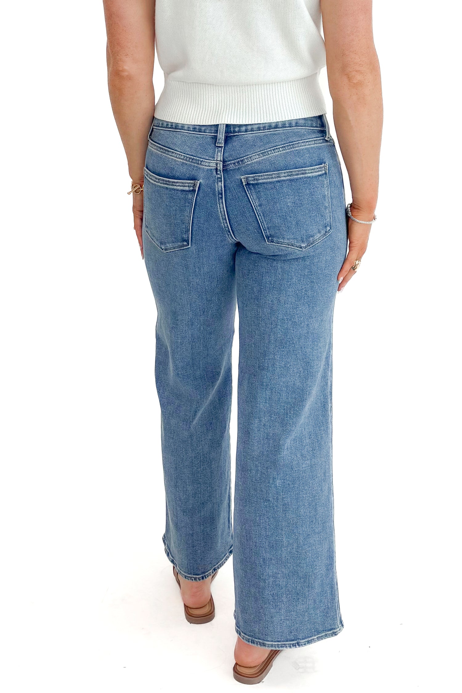 Back view of woman wearing Medium Wash Seam Detail Wide Leg Jeans by Just Black Denim with white top against white studio background.