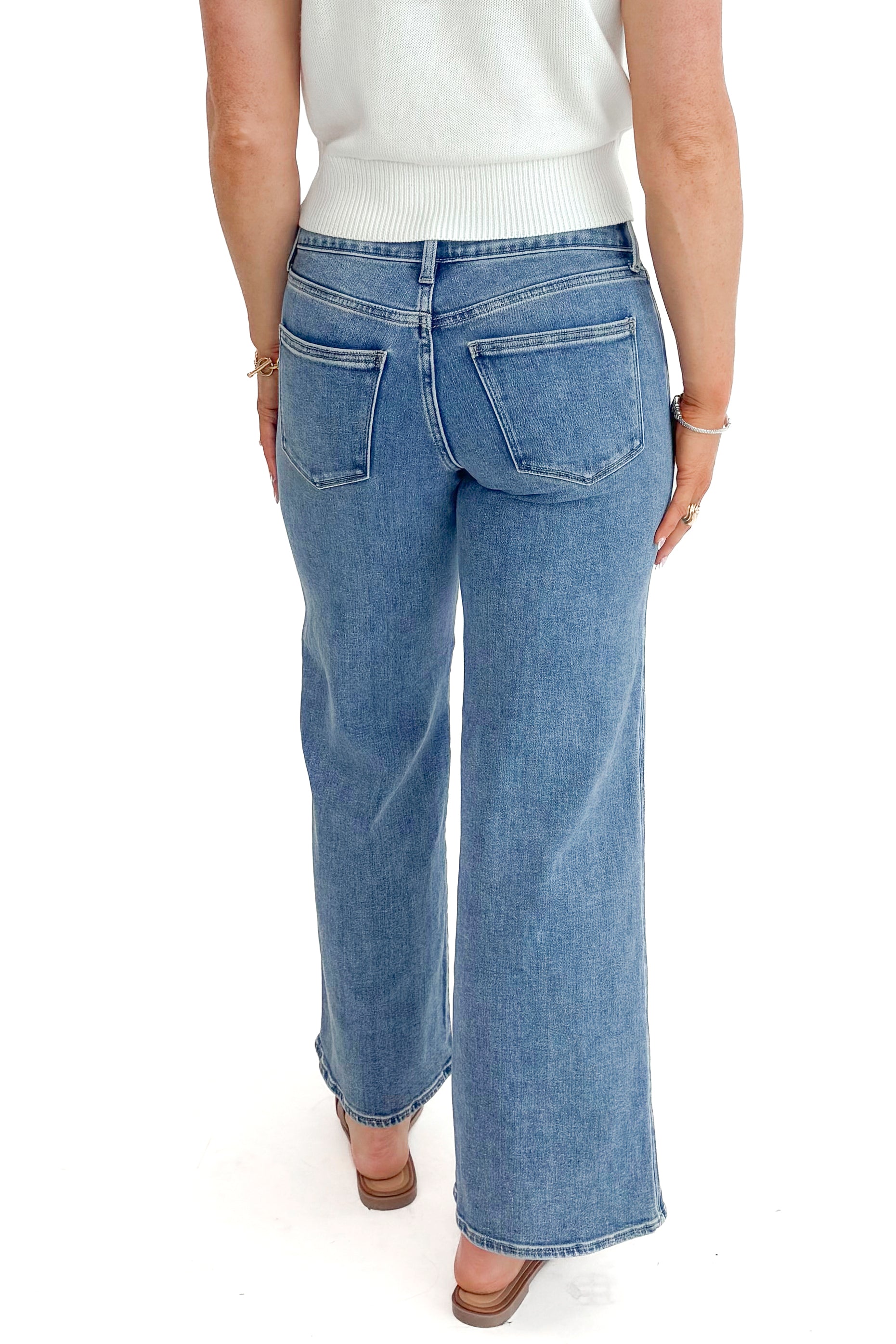 Back view of woman wearing Medium Wash Seam Detail Wide Leg Jeans by Just Black Denim with white top against white studio background.