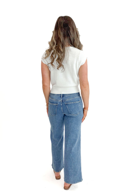 Back view of woman wearing Medium Wash Seam Detail Wide Leg Jeans by Just Black Denim with white top against white studio background.